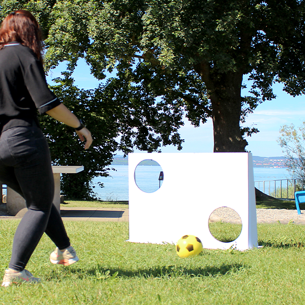 Woman playing with an unprinted goal wall and soft ball outdoors