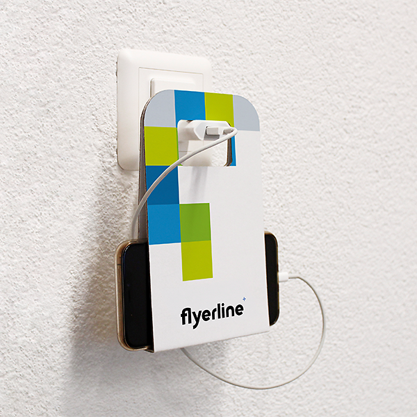 Cardboard Mobile Phone Stand holding a smartphone while charging at a wall socket