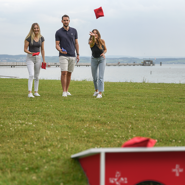 Drei Personen beim Cornhole-Spiel im Freien für Freizeit und Events